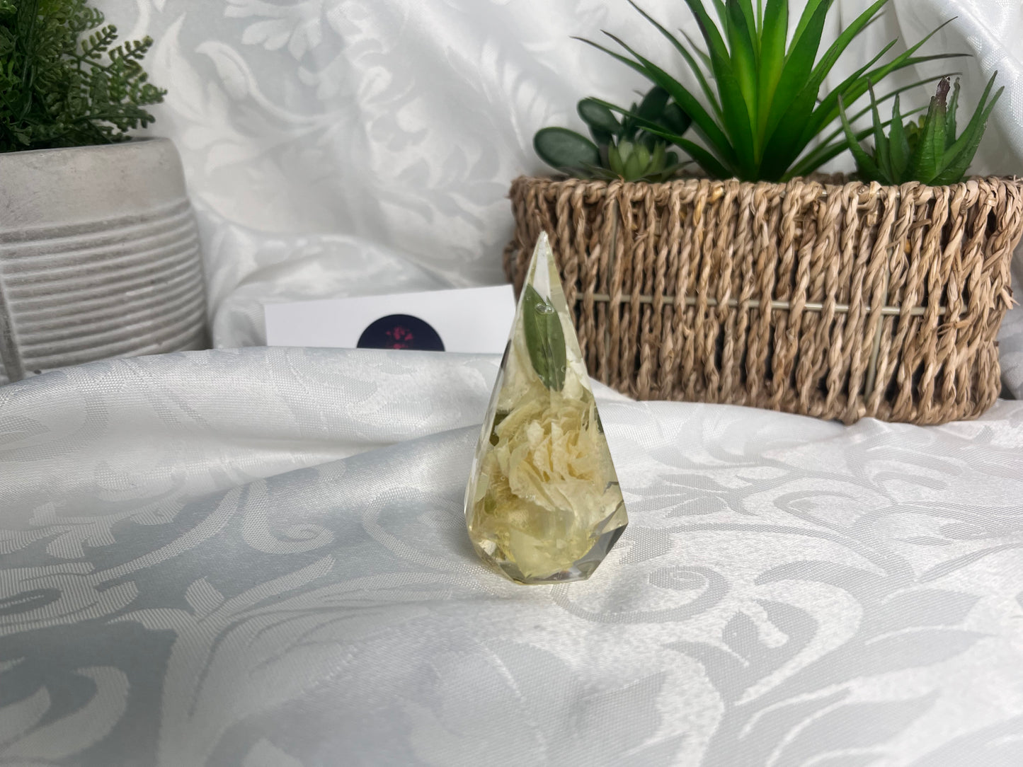White and green foliage inside a clear resin ring holder.